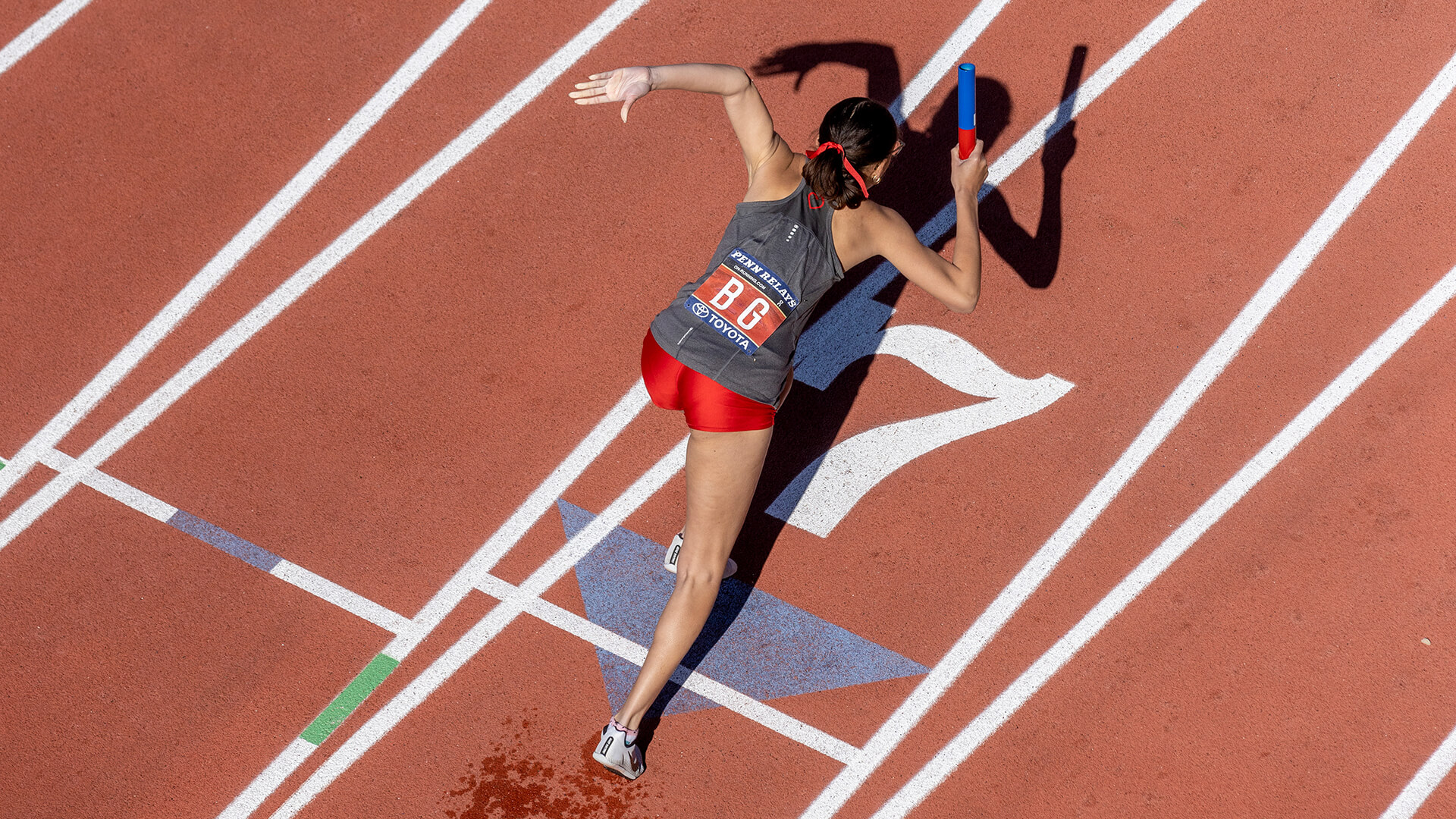 aerial view of a woman sprinting on a red track